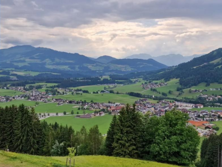 Bosrand met uitzicht over het dorp en de dalvlakte – Alpinolino Holzwurmweg, Westendorf