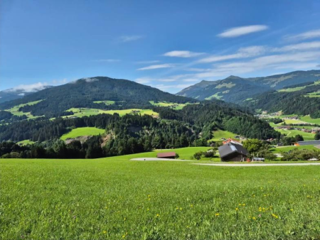 Golvende groene weiden met een almhut en bergen op de achtergrond – Sunnseitrunde vanuit Hopfgarten, Westendorf